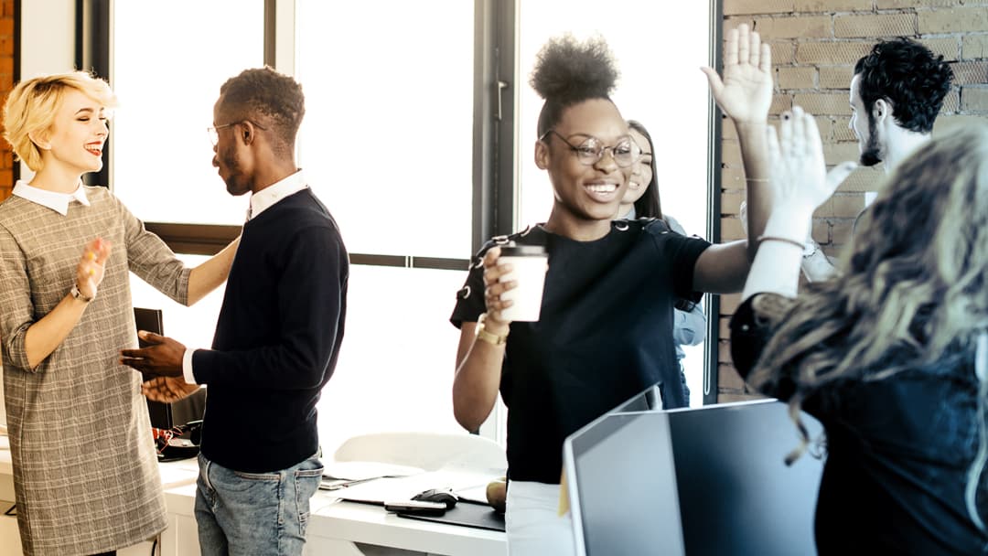 Office workers high-five each other.